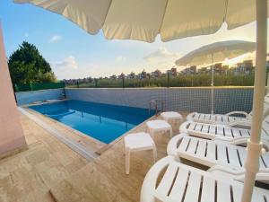 einen Pool mit weißen Stühlen und einem Sonnenschirm in der Unterkunft Villa Grau in Antalya/Belek in Belek