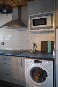 a kitchen with a washing machine and a microwave at La casa de la tía Antonia in Arenas de San Pedro