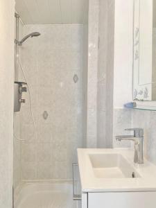 a white bathroom with a sink and a shower at Appartement vue mer Merlimont in Merlimont