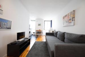 ein Wohnzimmer mit einem Sofa und einem TV in der Unterkunft Apartment in Castelo in Lissabon