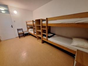 a room with three bunk beds and a chair at Youth Hostel Pinesta in Novigrad Istria