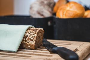 a cutting board with a knife and a loaf of bread at Boutiquehotel Caravella Velden by S4Y in Velden am Wörthersee