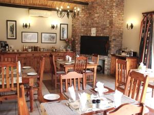 een eetkamer met tafels en stoelen en een televisie bij Bydand B&B in Addo