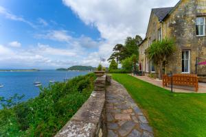 a house with a stone wall next to the water at Dungallan Country House Bed & Breakfast in Oban