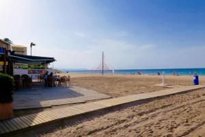 a beach with a bar and people on the beach at Casa Delicias con Piscina Privada a 200m playa - By Marina Alta Holidays in Denia
