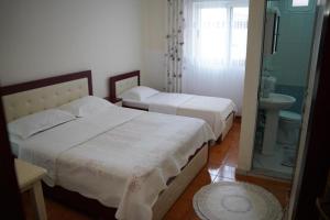 ein Schlafzimmer mit 2 Betten und ein Badezimmer mit einem Waschbecken in der Unterkunft Hotel Kalaja in Shkodra