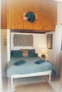 um quarto com uma cama azul e paredes de madeira em Quintinha Boheme… em Aljezur