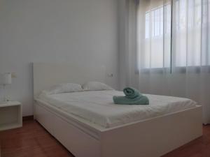 Una cama blanca con una toalla verde. en Ap4Us B1 - Apartment for us - Sightseeing & Beach At The Best Price, en Badalona