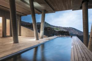 a swimming pool with a wooden deck and mountains in the background at ION Adventure Hotel, Nesjavellir, a Member of Design Hotels in Nesjavellir