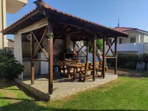 a wooden gazebo with a table and benches at Polynikis Apartment in Nikiti