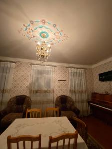 una sala da pranzo con tavolo, sedie e lampadario di Guest House Shateau a Sagarejo Altre 23 foto