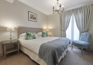 a bedroom with a bed and a chair and a chandelier at La Résidence de La Réserve in Beaulieu-sur-Mer