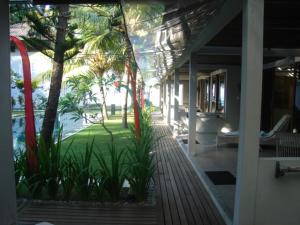 a porch of a house with palm trees and a pool at Aquaria Eco Resort in Candidasa