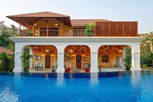 a house with a swimming pool in front of a house at amã Stays & Trails Hacienda De Bastora, Goa in Old Goa