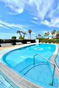 duży basen z niebieską wodą i palmami w obiekcie SeaHomes Vacations - MARINA BOUTIQUE design w Santa Susanna