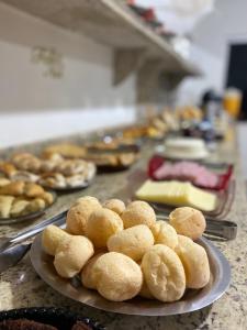 a plate of donuts on a counter with other pastries at Hotel Oliveira in Ouroeste