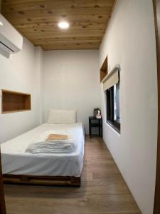 ein kleines Schlafzimmer mit einem Bett und einem Fenster in der Unterkunft Chill Lo 訂房後請收訊息確認 in Toufen
