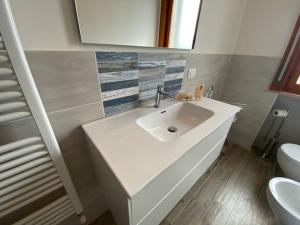 La salle de bains est pourvue d'un lavabo blanc et de toilettes. dans l'établissement Casa Diamante a pochi passi dal mare di Albenga, à Albenga
