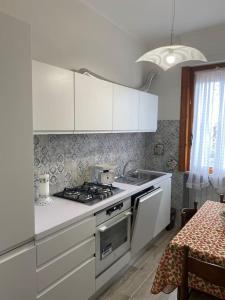 La cuisine est équipée de placards blancs et d'un four avec plaques de cuisson. dans l'établissement Casa Diamante a pochi passi dal mare di Albenga, à Albenga