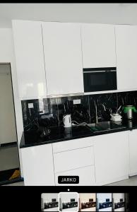 a kitchen with white cabinets and a black counter top at Apartmani K&V in Veliko Gradište