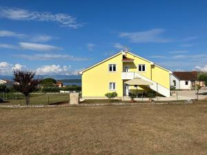 a white and yellow house with a yard at Sweet Lapat by EL-PI TOURS in Porat