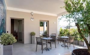 a patio with tables and chairs and trees at Cinque Venti BB Porto Cesareo in Porto Cesareo