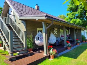 a house with a wooden deck with a patio at NAMIŅŠ PIE JŪRAS in Lapmežciems