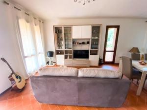 sala de estar con sofá y guitarra en B&B Peonia Sun light, en Capo Sperone