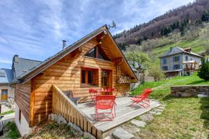 a wooden cabin with red chairs on a deck at Chalet Ornon in Ornon