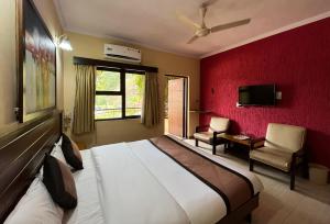 Hotel Sai leela - Shirdi في شيردي: غرفة نوم بسرير كبير وجدار احمر