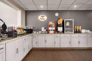 cocina con armarios blancos y encimera en Super 8 by Wyndham Gainesville TX, en Gainesville