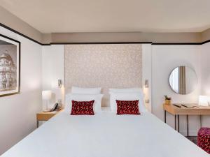 a bedroom with a large white bed with red pillows at Pullman La Pléiade Montpellier Centre in Montpellier