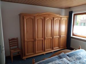 a bedroom with a wooden cabinet and a chair at Ferienwohnung Rühlmann in Detern