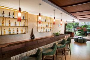 a bar with green chairs and bottles of wine at DoubleTree by Hilton Hotel Goa - Arpora - Baga in Baga