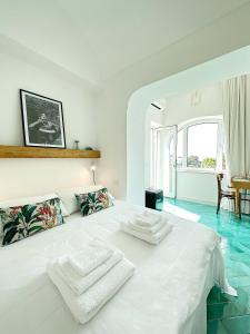 a white bedroom with a large white bed with two white towels at Dimora Storica Villa Pasquale Capri in Capri