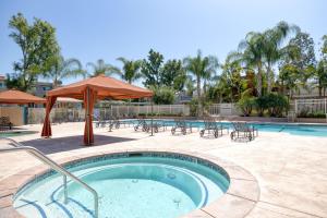 a hot tub with tables and chairs and an umbrella at Woodland Hills 1BR w pool gym nr Warner center LAX-893 in Los Angeles