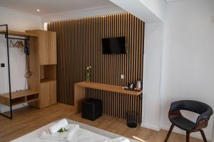 a hotel room with a chair and a television on a wall at Ampoulos Rooms & Apartments in Kedro