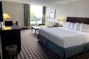 um quarto de hotel com uma cama grande e uma cadeira em Days Inn by Wyndham Fort Wright Cincinnati Area em Fort Wright