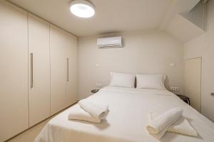 a bedroom with a large white bed with two white towels at Modern ground floor apt near the park in Athens