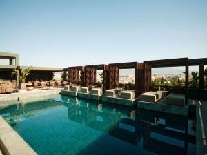 uma piscina com espreguiçadeiras e um edifício em Radisson Blu Park Hotel Athens em Atenas