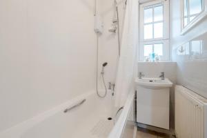 a white bathroom with a shower and a sink at Vauxhall Getaway in London