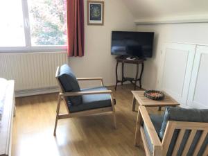 a living room with a tv and a chair and a table at Chambres Champêtres 