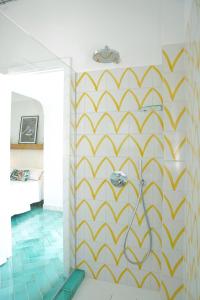 a bathroom with a yellow and white patterned wall at Dimora Storica Villa Pasquale Capri in Capri