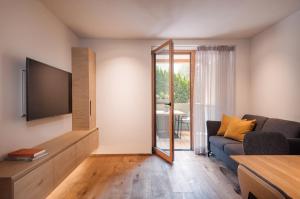 - un salon avec une télévision et un canapé dans l'établissement Max Green Wood Apartments, à Alpe di Siusi