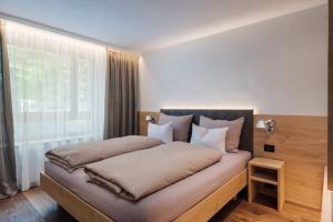 - une chambre avec un lit et une grande fenêtre dans l'établissement Max Green Wood Apartments, à Alpe di Siusi