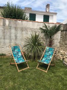 two beach chairs sitting in the grass next to a wall at Elégante maison familiale au cœur des remparts de la citadelle in Le Château-dʼOléron
