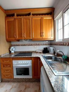 uma cozinha com armários de madeira e um lavatório em Casa Castillo Penthouse with balcony and solarium near La Zenia boulevard em Orihuela