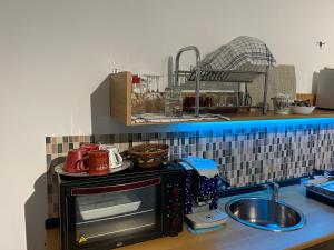 a kitchen counter with a microwave and a sink at Apulia Rooms in Taranto