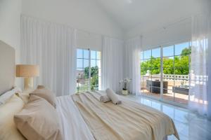 Dormitorio blanco con cama y ventana grande en VACATION MARBELLA I Villa Nadal, Private Pool, Lush Garden, Best Beaches at Your Doorstep, en Marbella
