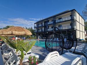 a resort with a swimming pool with chairs and a building at Ośrodek Promenada- Domki in Jastrzębia Góra